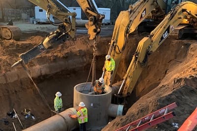 A group of construction workers are working on Phase 2B of an airport trunk main.