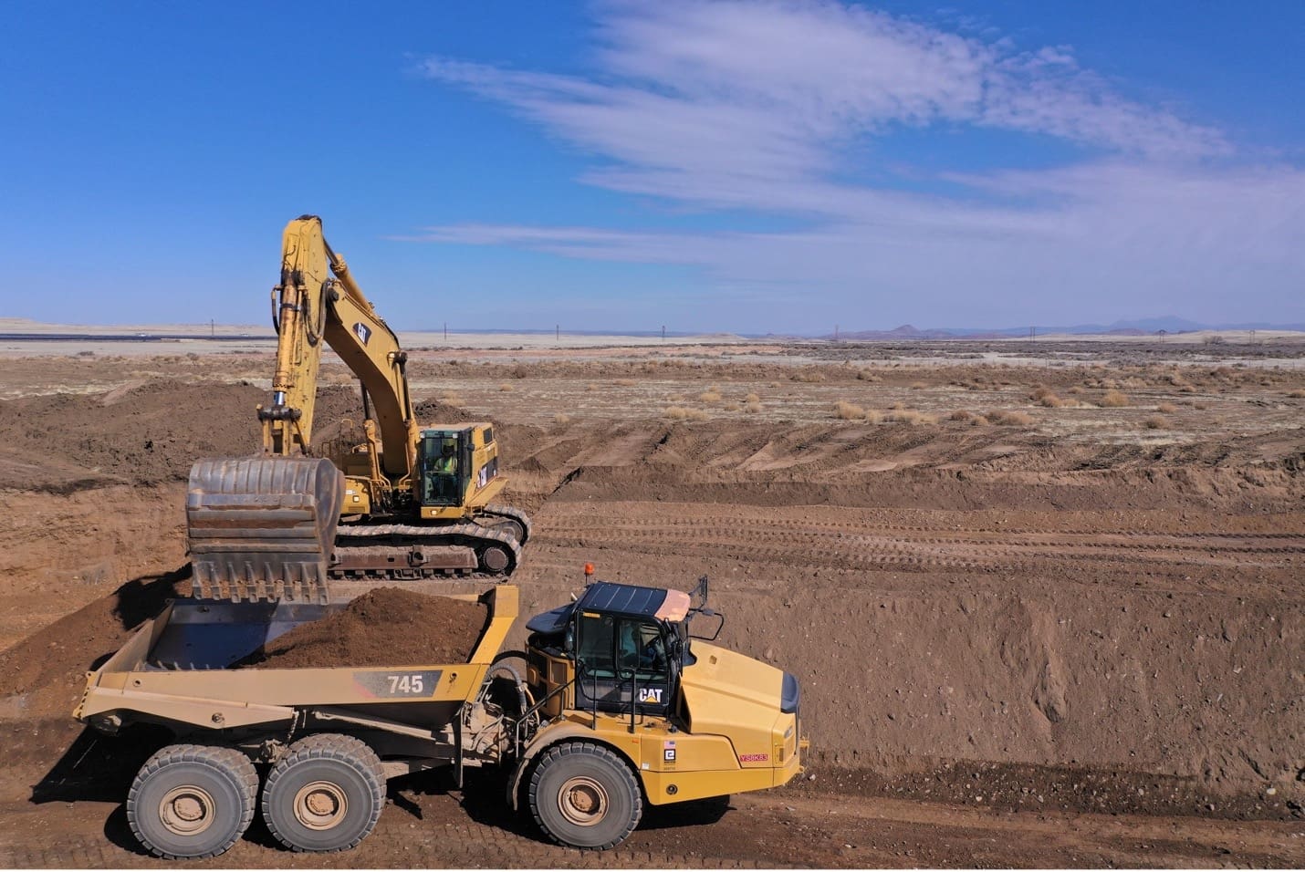 Two bulldozers from Martin-Marietta Material Hauling working on a dirt field.
