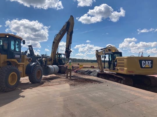 Two bulldozers on a dirt road.
