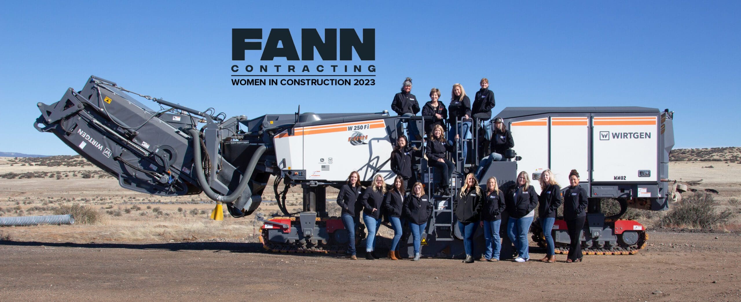 A group of people posing in front of an excavator.